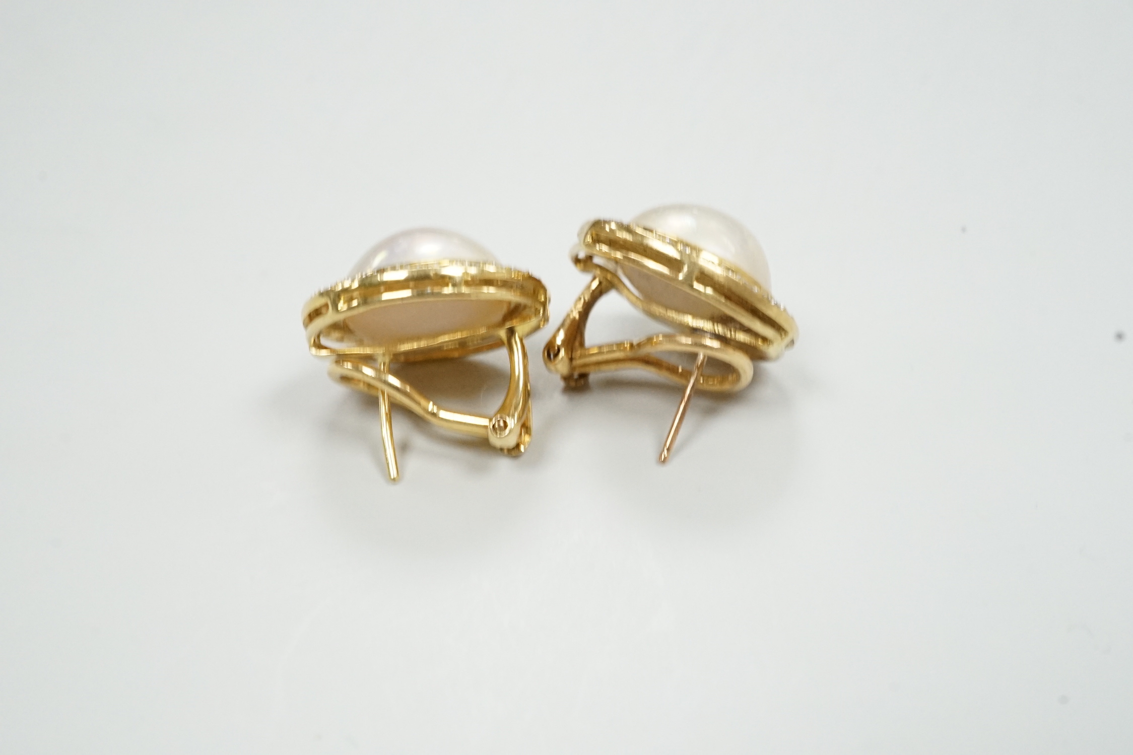 A pair of 750, mabe pearl and diamond cluster set circular earrings, diameter 18mm, gross weight 10.6 grams.